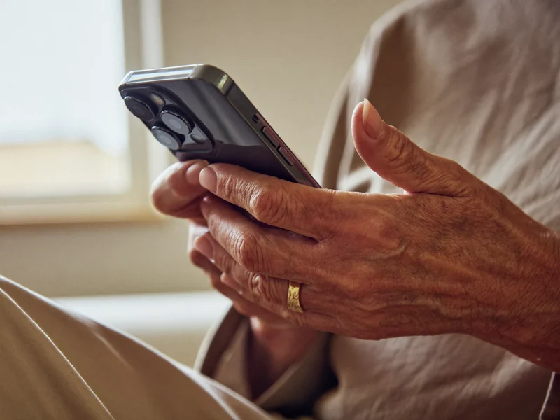 Primo piano di mani anziane che toccano lo schermo di uno smartphone